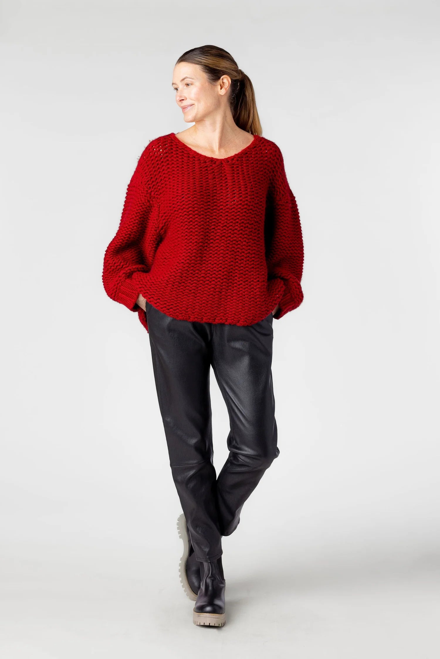 Woman wearing a red sweater and black pants on a white background
