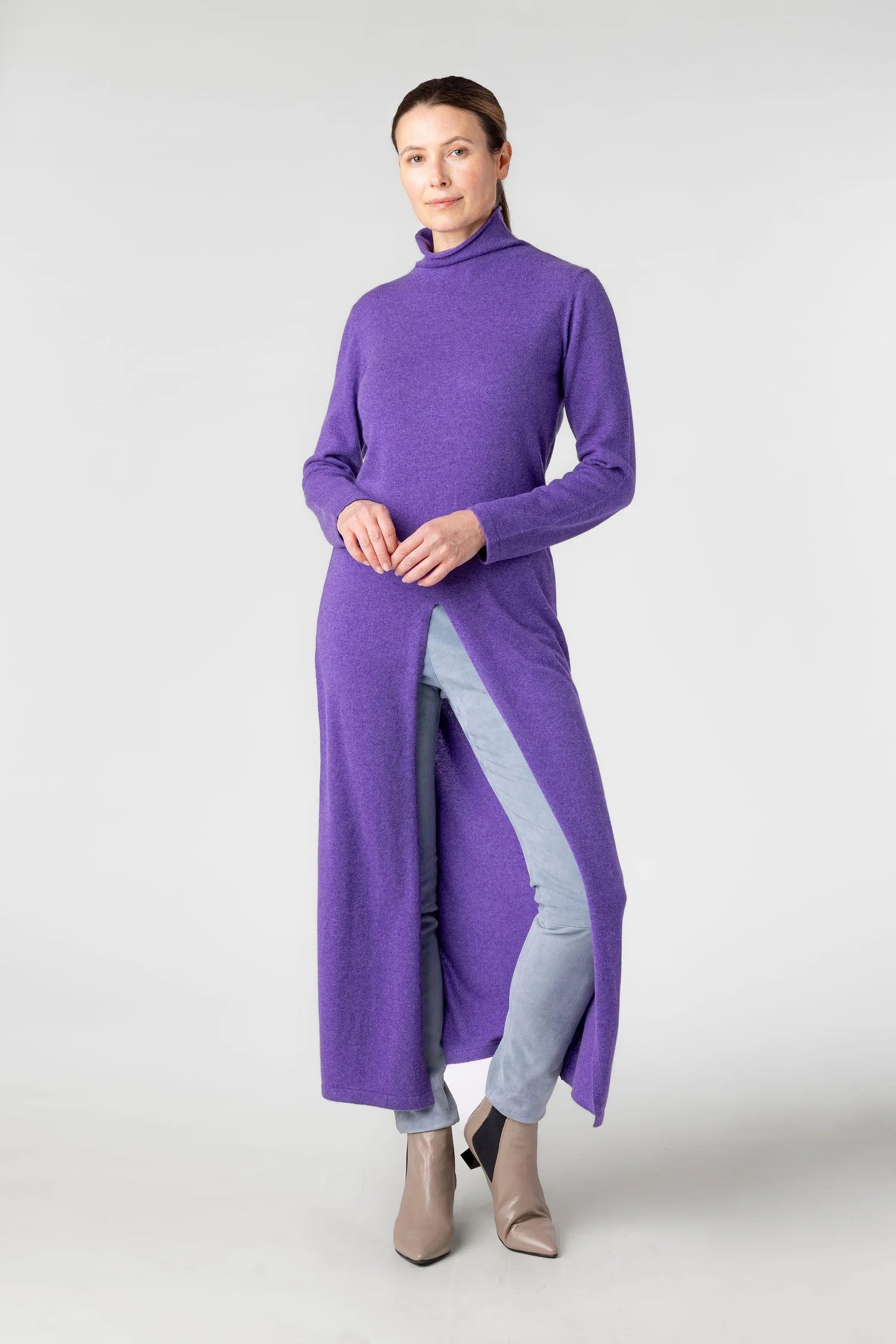 Woman wearing a long purple dress with a high collar on a white background