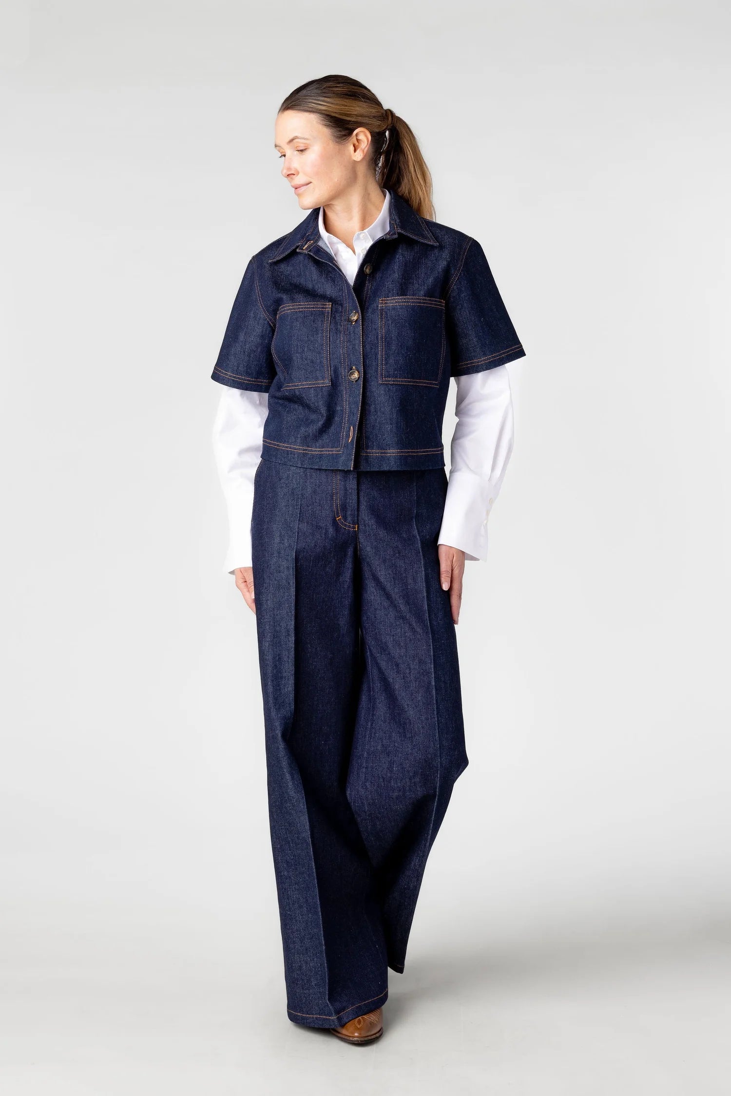 Woman wearing a denim outfit with a vest on a white background