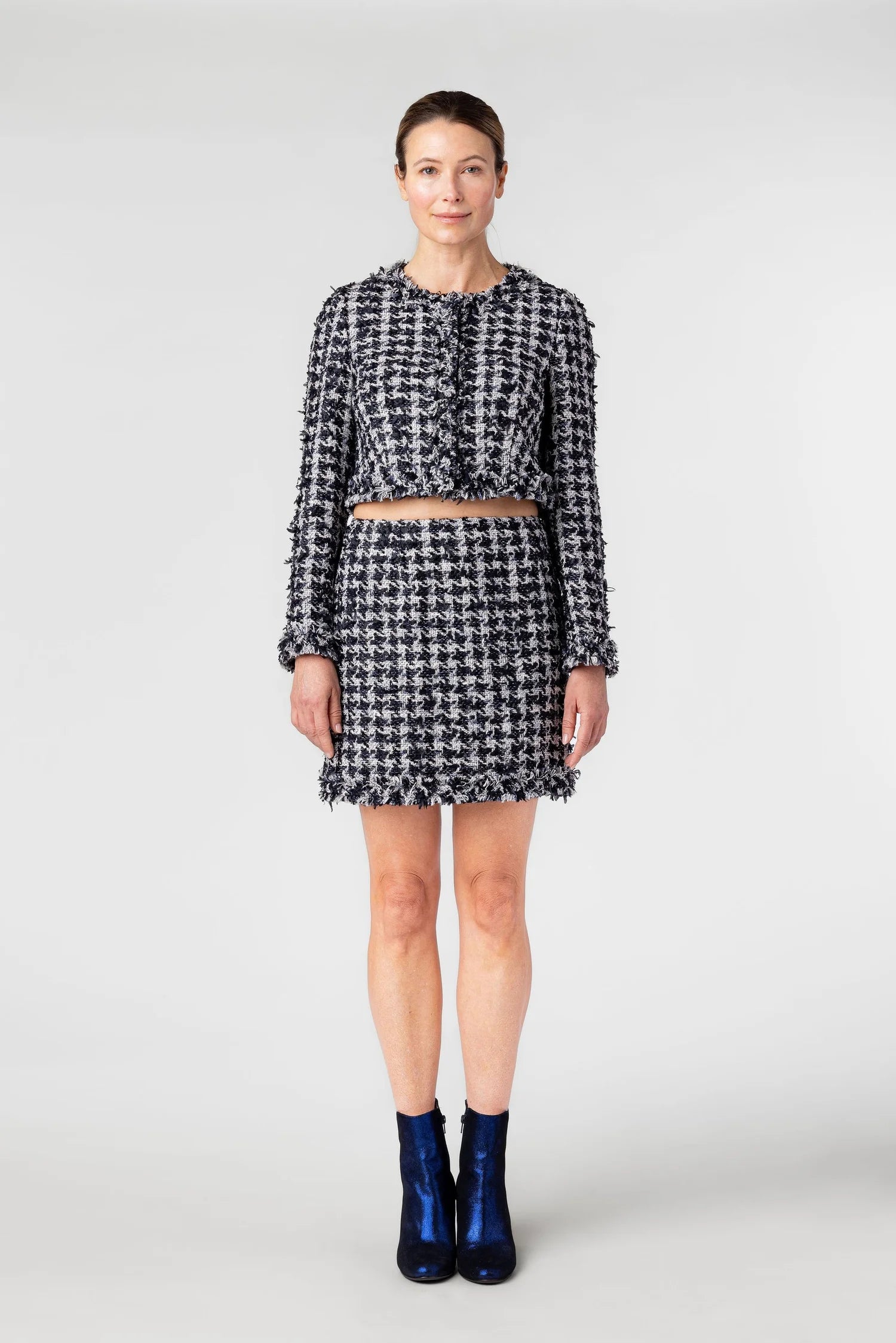 Woman wearing a black and white checkered outfit with blue shoes on a white background