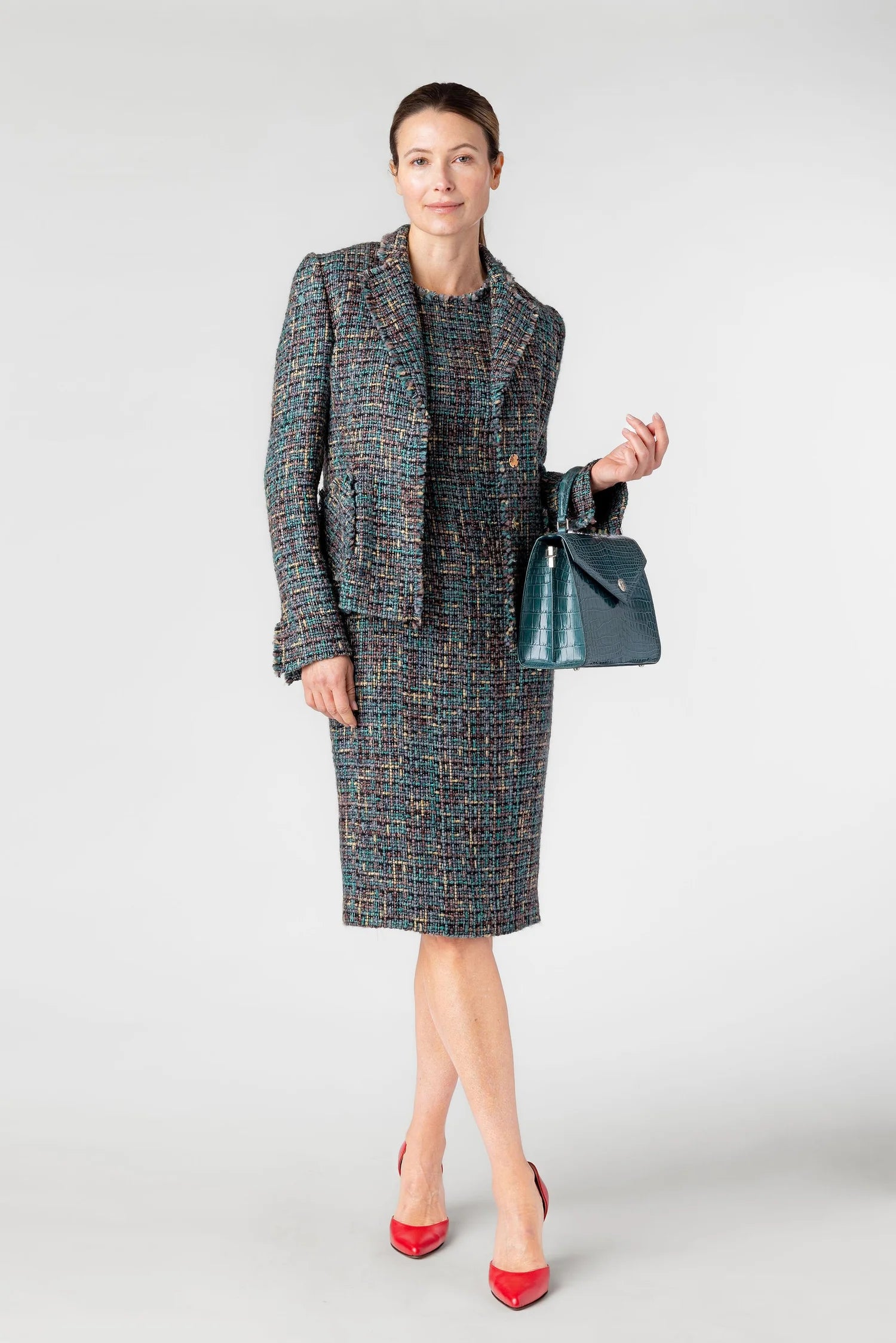 Woman wearing a patterned suit with a blue handbag on a white background