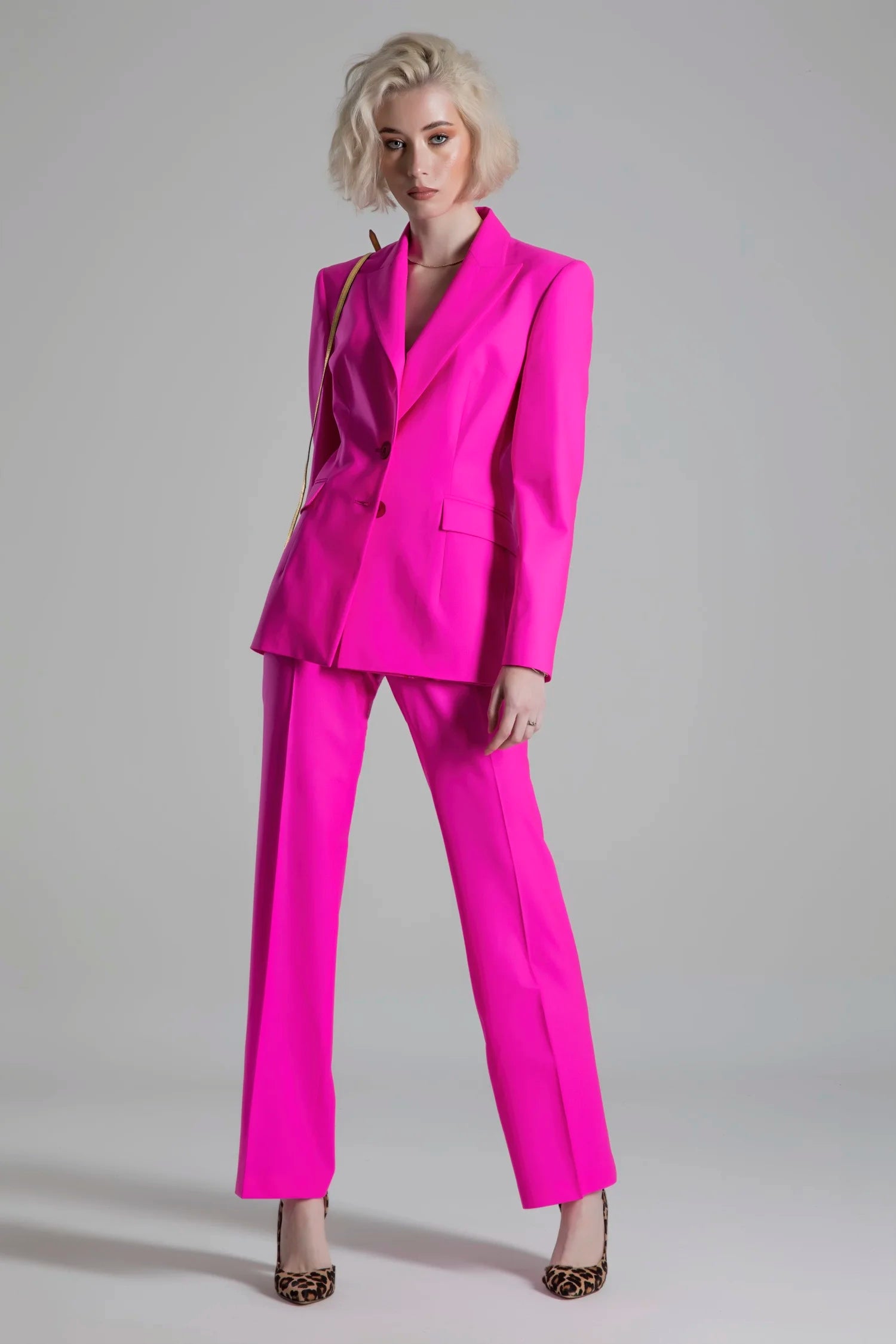 Woman wearing a bright pink suit against a gray background