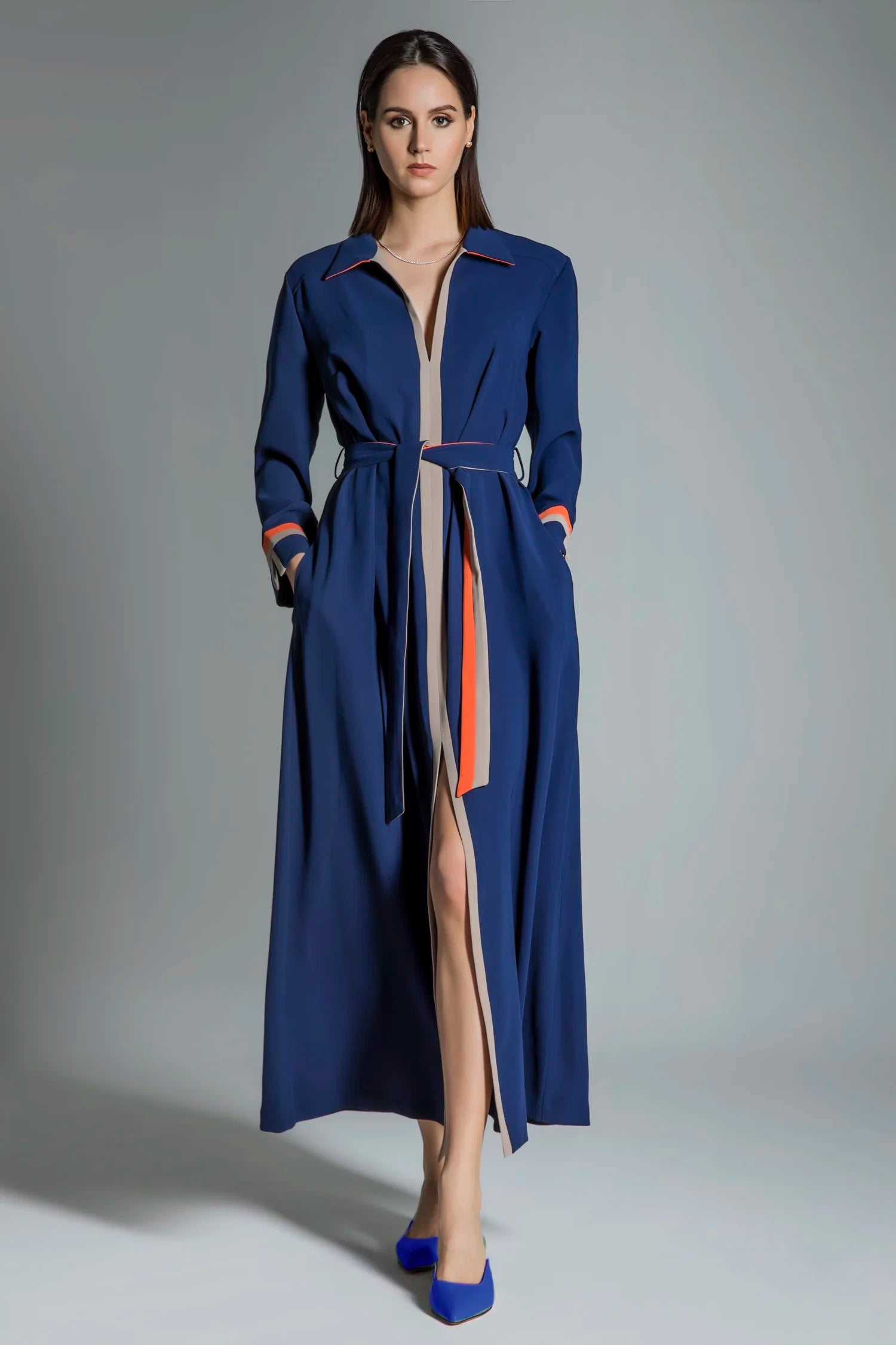 Woman wearing a long blue coat with a gray background