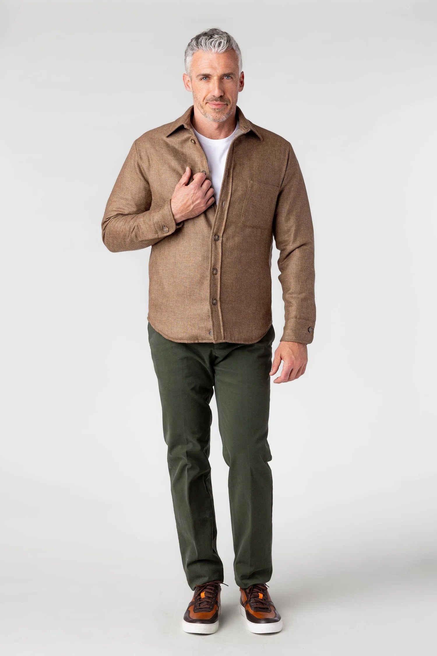 Man wearing a brown shirt and green pants on a white background