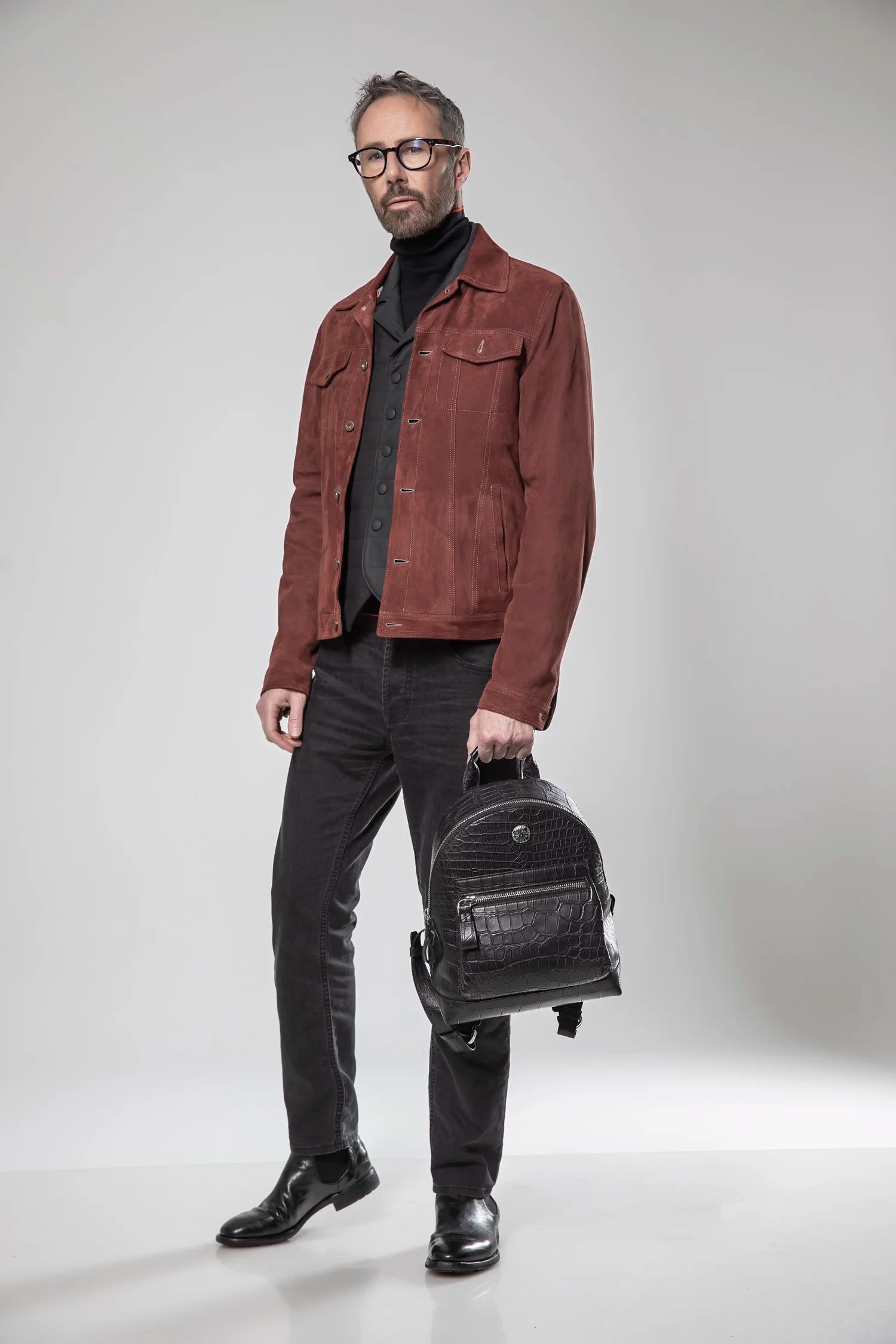 Man holding a black leather bag against a white background