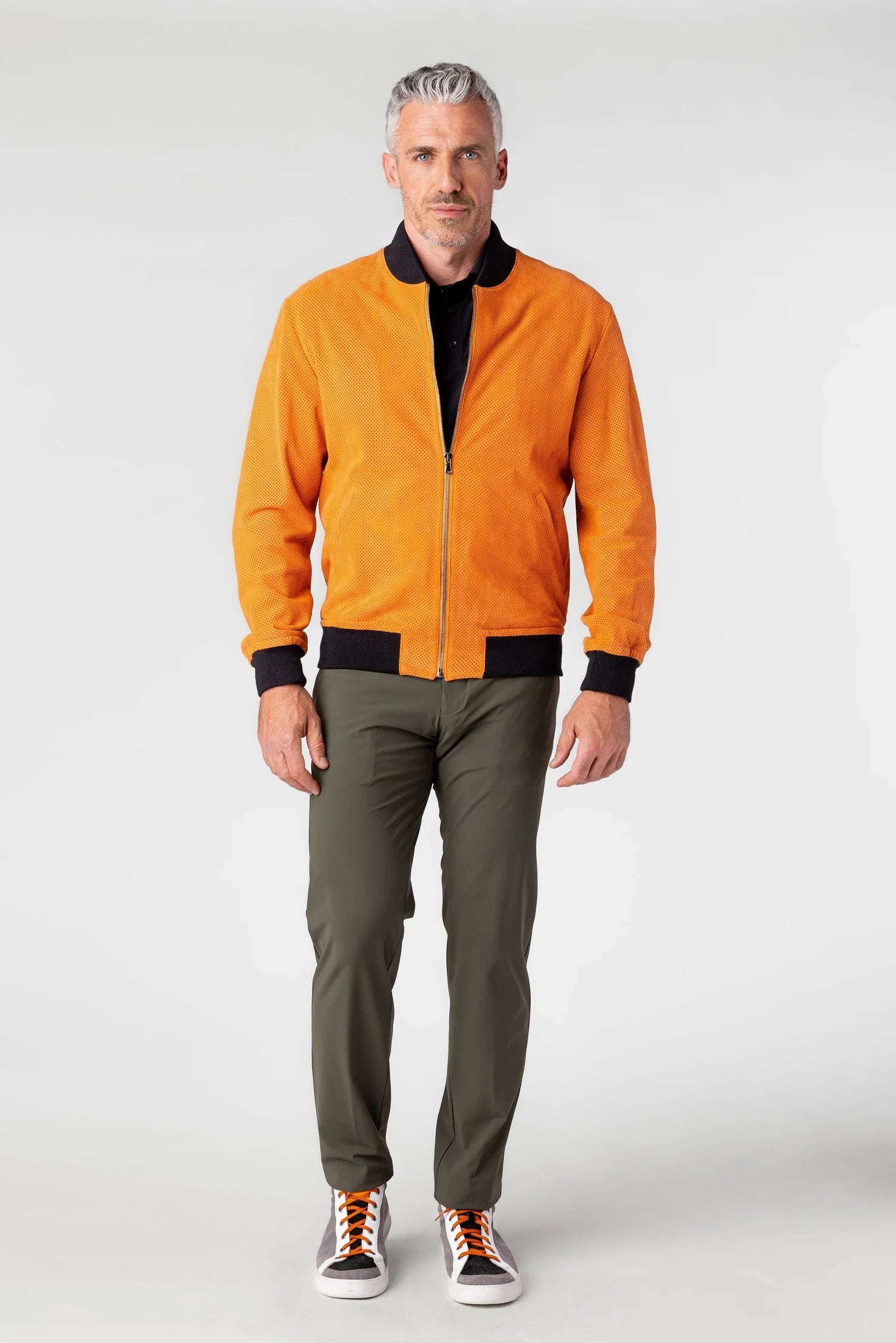 Man wearing an orange jacket and green pants on a white background