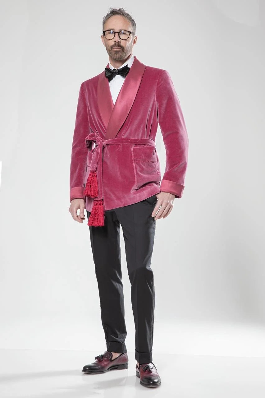 Man wearing a pink velvet jacket with a black bow tie on a white background