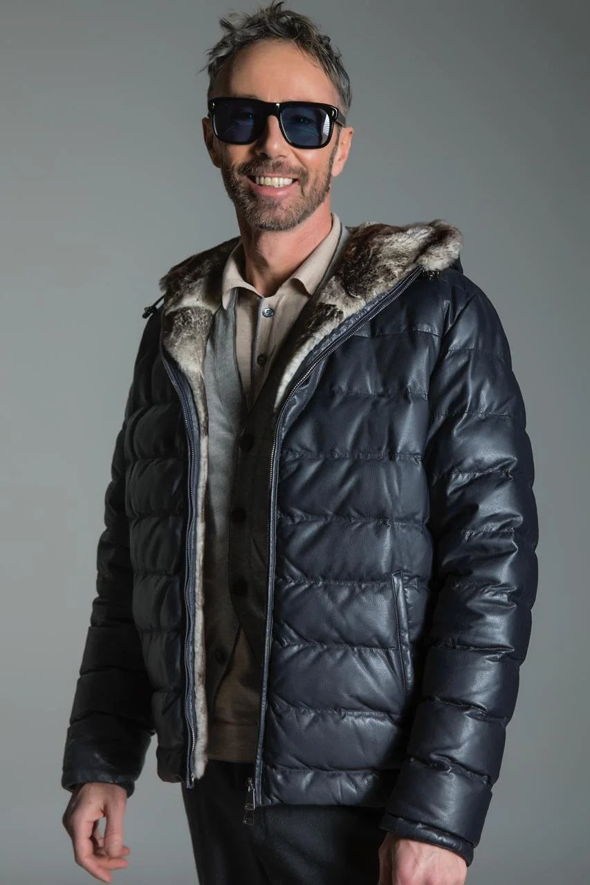 Man wearing a black puffer jacket with fur hood against a gray background